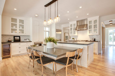 Mid-sized trendy u-shaped medium tone wood floor and brown floor eat-in kitchen photo in Calgary with a double-bowl sink, shaker cabinets, white cabinets, white backsplash, stainless steel appliances, an island, quartz countertops and subway tile backsplash