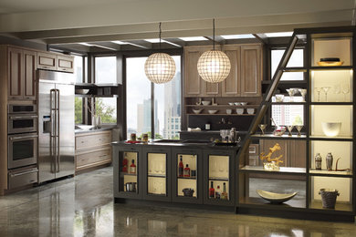 Bild på ett avskilt, stort funkis l-kök, med luckor med profilerade fronter, skåp i ljust trä, granitbänkskiva, grått stänkskydd, rostfria vitvaror och betonggolv