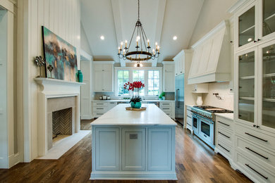 Example of a large transitional l-shaped medium tone wood floor enclosed kitchen design in Nashville with an undermount sink, shaker cabinets, white cabinets, marble countertops, gray backsplash, ceramic backsplash, stainless steel appliances and an island