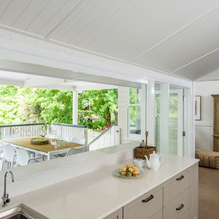Mid-sized contemporary galley open plan kitchen in Brisbane with open cabinets, granite benchtops, white splashback, with island, white benchtop, a drop-in sink, carpet and beige floor.