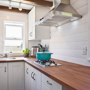 Small beach style l-shaped kitchen in Vancouver with a drop-in sink, flat-panel cabinets, white cabinets, wood benchtops, stainless steel appliances, dark hardwood floors, no island and shiplap splashback.
