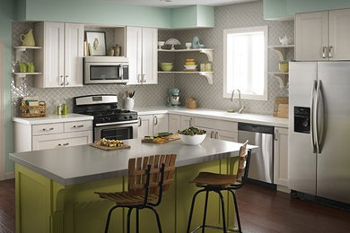 Foto de cocina clásica de tamaño medio con puertas de armario blancas, salpicadero verde, electrodomésticos de acero inoxidable, suelo de madera oscura y una isla