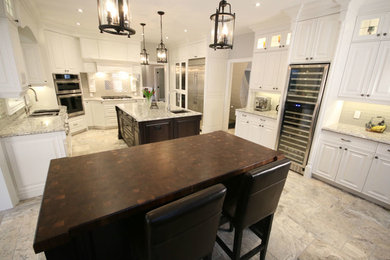 Inspiration for a huge timeless u-shaped kitchen remodel in Toronto with an undermount sink, raised-panel cabinets, white cabinets, quartz countertops, beige backsplash, glass tile backsplash, stainless steel appliances and two islands