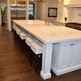 Immagine di un'ampia cucina chic con lavello stile country, ante a filo, ante bianche, top in quarzite, paraspruzzi bianco, paraspruzzi in gres porcellanato, elettrodomestici in acciaio inossidabile, parquet scuro, isola, pavimento marrone, top bianco e soffitto a cassettoni
