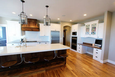 Eat-in kitchen - huge traditional l-shaped medium tone wood floor eat-in kitchen idea in Boise with a farmhouse sink, recessed-panel cabinets, white cabinets, granite countertops, white backsplash, stainless steel appliances and an island