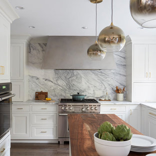 Mid-sized transitional eat-in kitchen pictures - Eat-in kitchen - mid-sized transitional u-shaped medium tone wood floor and brown floor eat-in kitchen idea in Chicago with an undermount sink, shaker cabinets, white cabinets, wood countertops, white backsplash, stone slab backsplash, stainless steel appliances, an island and brown countertops