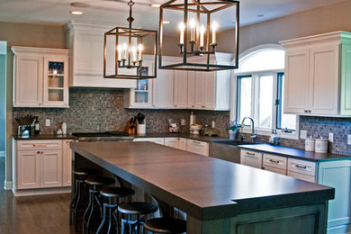 Elegant l-shaped eat-in kitchen photo in Cleveland with a farmhouse sink, recessed-panel cabinets, white cabinets, quartz countertops, multicolored backsplash, mosaic tile backsplash and stainless steel appliances