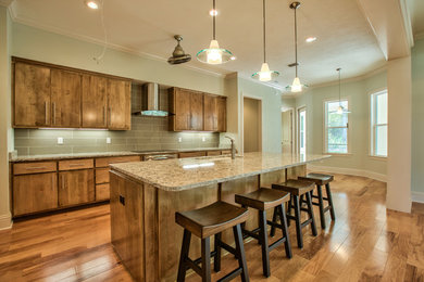 Example of a large transitional l-shaped medium tone wood floor open concept kitchen design in Atlanta with an undermount sink, flat-panel cabinets, medium tone wood cabinets, granite countertops, green backsplash, matchstick tile backsplash, stainless steel appliances and an island