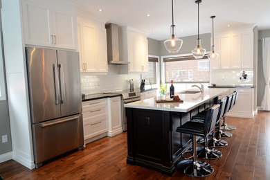 Open concept kitchen - mid-sized transitional l-shaped medium tone wood floor open concept kitchen idea in Toronto with shaker cabinets, granite countertops, white backsplash, subway tile backsplash, stainless steel appliances, an island, a double-bowl sink and white cabinets