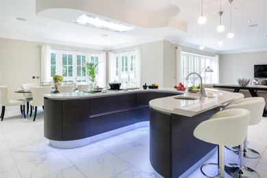 This is an example of a medium sized contemporary u-shaped kitchen in Berkshire with flat-panel cabinets, black cabinets, an island and white floors.