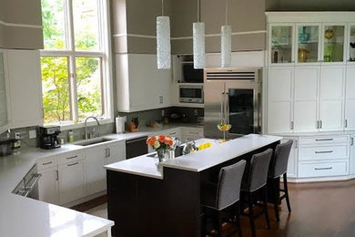 Moderne Wohnküche in U-Form mit Einbauwaschbecken, Schrankfronten im Shaker-Stil, weißen Schränken, Quarzit-Arbeitsplatte, Küchengeräten aus Edelstahl, braunem Holzboden und Kücheninsel in Cincinnati