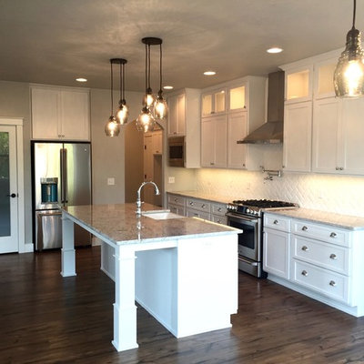 Eat-in kitchen - mid-sized craftsman l-shaped medium tone wood floor eat-in kitchen idea in Other with a farmhouse sink, shaker cabinets, white cabinets, granite countertops, white backsplash, ceramic backsplash, stainless steel appliances and an island