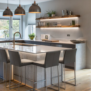 Photo of a modern l-shaped kitchen in Other with a submerged sink, flat-panel cabinets, grey cabinets, light hardwood flooring, an island, beige floors and white worktops.