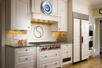Example of a classic kitchen design in Chicago with stainless steel appliances, white cabinets, granite countertops, beige backsplash and ceramic backsplash