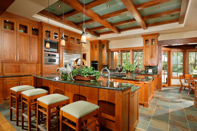 サクラメントにある広いおしゃれなマルチアイランドキッチン (シェーカースタイル扉のキャビネット、中間色木目調キャビネット、緑のキッチンパネル、石スラブのキッチンパネル、シルバーの調理設備、スレートの床) の写真