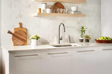 Foto de cocina contemporánea de tamaño medio con fregadero encastrado, armarios con paneles lisos, puertas de armario blancas, salpicadero blanco, electrodomésticos de acero inoxidable y encimeras blancas