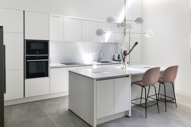 Modern inredning av ett stort vit vitt kök, med en integrerad diskho, släta luckor, vita skåp, bänkskiva i kvarts, vitt stänkskydd, stänkskydd i keramik, rostfria vitvaror, klinkergolv i keramik, en köksö och grått golv