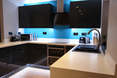 Foto de cocina minimalista de tamaño medio sin isla con armarios con paneles lisos, puertas de armario negras, encimera de cuarcita y encimeras blancas