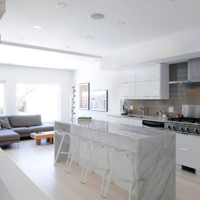 Example of a mid-sized danish single-wall light wood floor eat-in kitchen design in Ottawa with an undermount sink, flat-panel cabinets, white cabinets, marble countertops, gray backsplash, porcelain backsplash, stainless steel appliances and an island