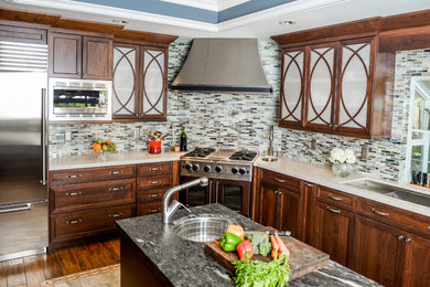 Example of a mid-sized transitional l-shaped ceramic tile eat-in kitchen design in Orange County with an undermount sink, glass-front cabinets, dark wood cabinets, quartz countertops, multicolored backsplash, mosaic tile backsplash, stainless steel appliances and an island