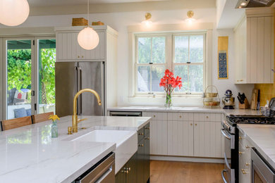 サンフランシスコにあるおしゃれなキッチン (エプロンフロントシンク、インセット扉のキャビネット、白いキャビネット、黄色いキッチンパネル、シルバーの調理設備、淡色無垢フローリング、白いキッチンカウンター) の写真