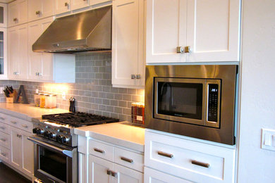 Example of an arts and crafts l-shaped dark wood floor eat-in kitchen design in Salt Lake City with an island, shaker cabinets, white cabinets, marble countertops, gray backsplash, subway tile backsplash, stainless steel appliances and an undermount sink