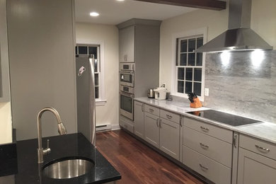 This is an example of a large traditional l-shaped kitchen/diner in Baltimore with a submerged sink, shaker cabinets, white cabinets, marble worktops, grey splashback, stone slab splashback, stainless steel appliances, dark hardwood flooring and an island.