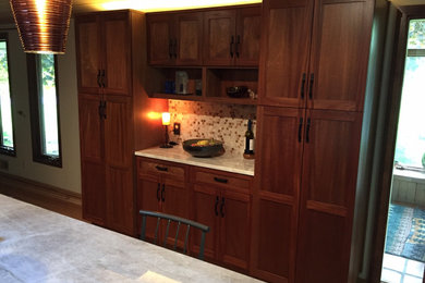 Foto de cocina comedor tradicional renovada de tamaño medio con armarios estilo shaker, puertas de armario de madera en tonos medios, electrodomésticos de acero inoxidable, suelo de madera en tonos medios, una isla y encimeras blancas