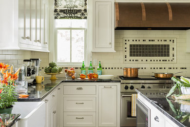 Example of a brown floor eat-in kitchen design in Boston with white cabinets, white backsplash, subway tile backsplash, stainless steel appliances, an island and black countertops
