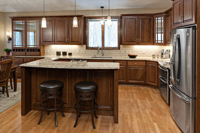 Photo of a traditional kitchen in Minneapolis with a submerged sink, raised-panel cabinets, medium wood cabinets, engineered stone countertops, beige splashback, ceramic splashback, stainless steel appliances, light hardwood flooring and an island.