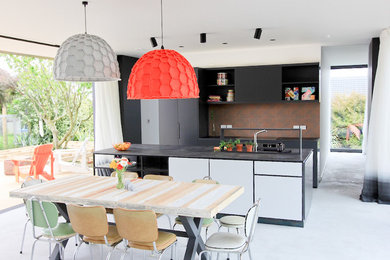 Стильный дизайн: прямая кухня-гостиная в современном стиле с двойной мойкой, плоскими фасадами, черными фасадами, коричневым фартуком, островом и серым полом - последний тренд