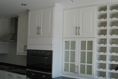 Kitchen - large traditional l-shaped kitchen idea in Toronto with an undermount sink, raised-panel cabinets, white cabinets, granite countertops, stainless steel appliances and an island