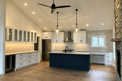 Inspiration for a large modern u-shaped light wood floor and beige floor kitchen pantry remodel in Vancouver with a double-bowl sink, shaker cabinets, white cabinets, quartz countertops, white backsplash, subway tile backsplash, stainless steel appliances, an island and gray countertops