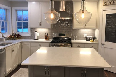 Large elegant u-shaped vinyl floor and brown floor eat-in kitchen photo in Other with a double-bowl sink, flat-panel cabinets, white cabinets, quartzite countertops, gray backsplash, ceramic backsplash, stainless steel appliances, an island and white countertops