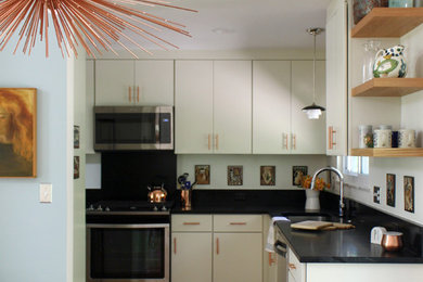 Foto på ett 60 tals kök, med en undermonterad diskho, vita skåp, bänkskiva i täljsten, rostfria vitvaror och mellanmörkt trägolv
