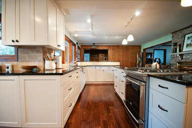 Inspiration for a large timeless medium tone wood floor enclosed kitchen remodel in Minneapolis with a farmhouse sink, recessed-panel cabinets, white cabinets, granite countertops, beige backsplash, ceramic backsplash, stainless steel appliances and an island