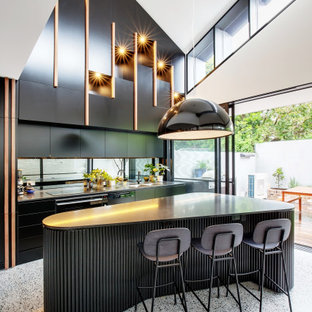 Mid-sized contemporary single-wall open plan kitchen in Other with a double-bowl sink, flat-panel cabinets, black cabinets, metallic splashback, mirror splashback, terrazzo floors, with island and multi-coloured floor.