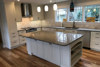 Example of a large trendy u-shaped light wood floor and multicolored floor eat-in kitchen design in Baltimore with an undermount sink, shaker cabinets, white cabinets, granite countertops, multicolored backsplash, marble backsplash, stainless steel appliances, an island and multicolored countertops