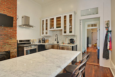 Kleine Moderne Wohnküche in U-Form mit profilierten Schrankfronten, weißen Schränken, Marmor-Arbeitsplatte, Küchenrückwand in Weiß, Rückwand aus Steinfliesen, Landhausspüle und braunem Holzboden in New Orleans