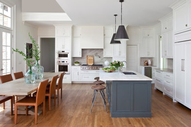 Transitional l-shaped medium tone wood floor and brown floor eat-in kitchen photo in Atlanta with an undermount sink, shaker cabinets, white cabinets, gray backsplash, stone slab backsplash, paneled appliances, an island and gray countertops