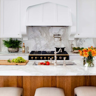 Example of a mid-sized classic l-shaped medium tone wood floor kitchen design in Atlanta with an undermount sink, marble countertops, white backsplash, paneled appliances, recessed-panel cabinets, white cabinets, an island and marble backsplash