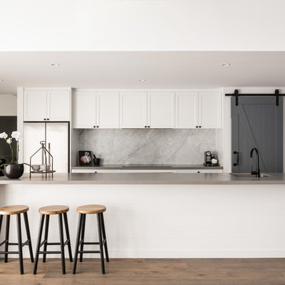 Transitional galley medium tone wood floor and brown floor kitchen photo in Perth with an undermount sink, shaker cabinets, white cabinets, gray backsplash, stone slab backsplash, stainless steel appliances, an island and gray countertops