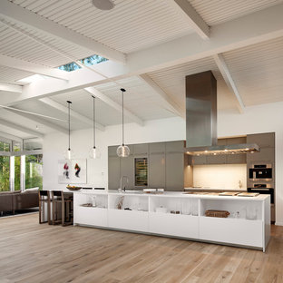 Inspiration for a large 1950s galley medium tone wood floor and beige floor open concept kitchen remodel in Santa Barbara with flat-panel cabinets, gray cabinets, white backsplash, an island and stainless steel appliances