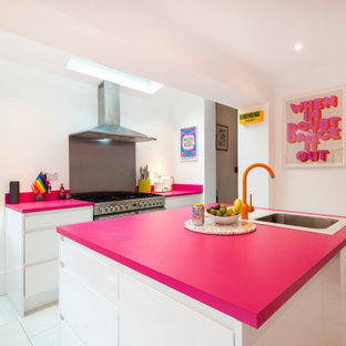 Inredning av ett eklektiskt mellanstort rosa rosa kök, med en integrerad diskho, släta luckor, vita skåp, bänkskiva i koppar, rosa stänkskydd, rostfria vitvaror, klinkergolv i keramik, en köksö och vitt golv