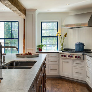 Foto di una grande cucina classica con lavello sottopiano, ante in stile shaker, ante bianche, paraspruzzi bianco, paraspruzzi in legno, elettrodomestici in acciaio inossidabile, pavimento in legno massello medio, isola, pavimento marrone e top in granito