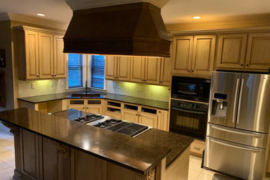 Example of a large tuscan u-shaped terra-cotta tile and brown floor kitchen design in Birmingham with an undermount sink, raised-panel cabinets, distressed cabinets, quartz countertops, beige backsplash, marble backsplash, stainless steel appliances, an island and brown countertops