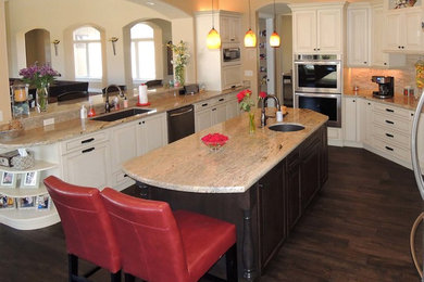 Eat-in kitchen - large traditional dark wood floor eat-in kitchen idea in Other with an undermount sink, raised-panel cabinets, white cabinets, granite countertops, beige backsplash, matchstick tile backsplash, stainless steel appliances and an island