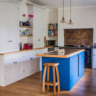 Diseño de cocina comedor en U, rústica, grande, con armarios estilo shaker, puertas de armario grises, encimera de granito, electrodomésticos negros, una isla, fregadero bajoencimera, salpicadero metalizado, salpicadero de metal y suelo de madera clara