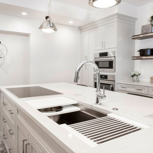 This is an example of a mid-sized transitional single-wall eat-in kitchen in Other with an undermount sink, quartzite benchtops, white splashback, stainless steel appliances, vinyl floors, with island, brown floor, shaker cabinets, grey cabinets and porcelain splashback.