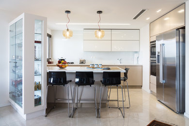 Medium sized contemporary kitchen in Tel Aviv with flat-panel cabinets, marble worktops, white splashback, glass sheet splashback, stainless steel appliances, ceramic flooring and an island.